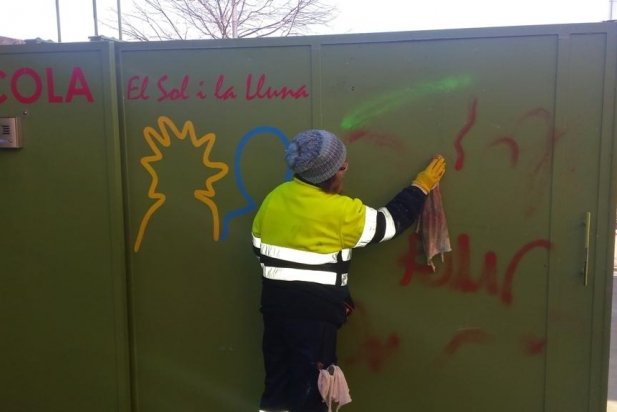 Una treballadora treu les pintades a l'entrada de l'escola_617x412