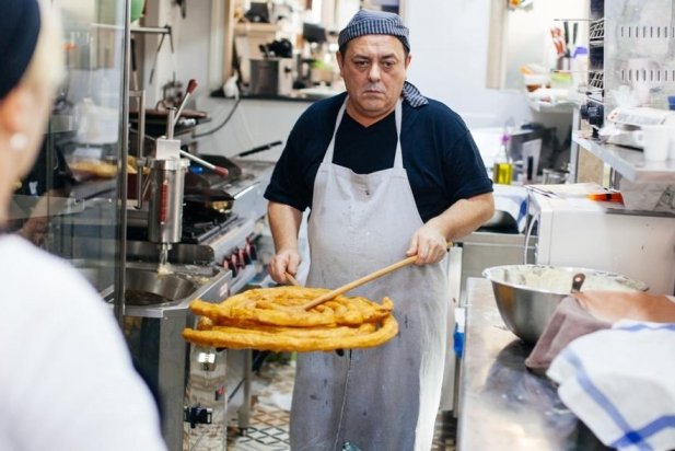 El xurrero Javi Perea, del Perea's Bar,  treu una 'rosca' de la xurrera per tallar-la en racions i servir-la_617x412