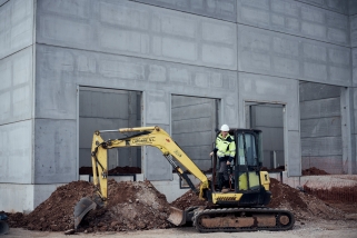 Un operari treballa amb una excavadora en la construcció d'una nau