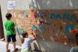 Diversos nens pintant en el mural participatiu solidari