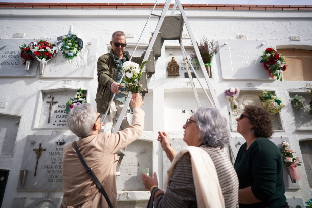 Familiars col·locant flors davant d'un nínxol