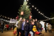 Una família es fa una foto davant del tió i de l'arbre de la Fira de Nadal