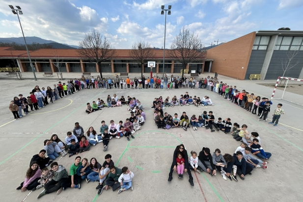 Alumnes, famílies, mestres i equip directiu de l'escola Mestre Pla formant el número 25 al pati de l'escola