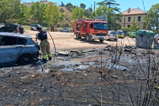 Els bombers apagant el foc del vehicle al costat de les restes de contenidors