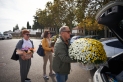 Una família amb diversos rams i centres de flors al pàrquing del cementiri el dia de Tots Sants de l'any passat